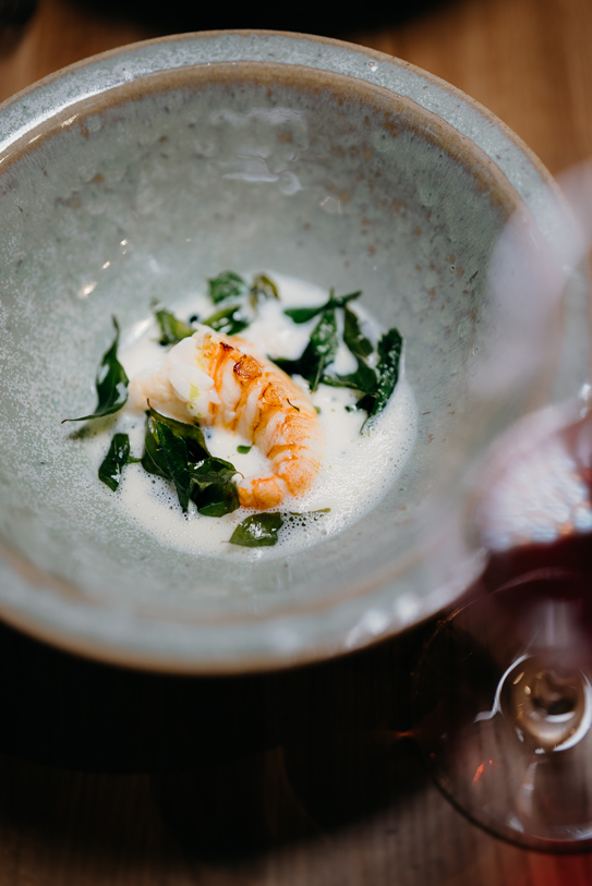 Grilled langoustine with foamed sauce and greens served in a ceramic bowl at Peonee Restaurant Canberra.