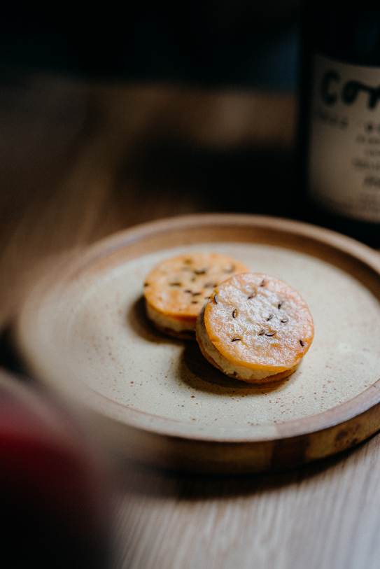 Two golden baked savory bites served on a rustic ceramic plate at Peonee Restaurant in Canberra.