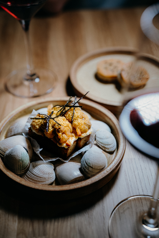 Gourmet seafood dish served with wine at Peonee Restaurant Canberra on a wooden table.